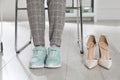 High heeled shoes near businesswoman wearing comfortable sneakers in office, closeup Royalty Free Stock Photo