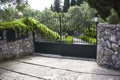 High Iron Gated Driveway Entrance of a Villa. Architectural Garden Landscape Surrounding the Curbed Pathway. Stone and Royalty Free Stock Photo