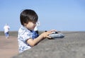 High key light little boy playing with soldiers and tank toys by the sea in hot sunny day summer, Kid playing wars and peace on hi