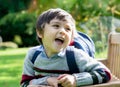 High key light portrait happy boy sitting on wooden bench in the garden with sunligh in morning, Cute mixed race kid relaxing in Royalty Free Stock Photo