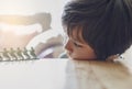 High key light portrait of lonly kid boy with sad face playing alone, Bored Child lying head donw on table looking at soldier toy