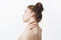 High key. Stunning good-looking caucasian young woman with dark long hair in bun hairdo holding neck with hands, turning