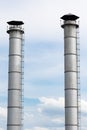 High large metal pipes of the plant gray color against the cloud light blue sky. Vertical photo of industrial metal structure