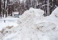 A high large snowdrift by the road against the backdrop of a city street Royalty Free Stock Photo