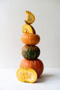 High long pyramid of a variety of whole and pieces of pumpkins on a white concrete background Royalty Free Stock Photo