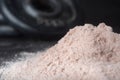 High magnification close up shot of pile of whey protein powder with weight plate behind