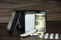 High medical costs and expensive treatment. Tablets and dollars in a tin can. Paid medicine. Health care concept and health system Royalty Free Stock Photo