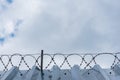 High metal corrugated wall with barbed wire and gray sky Royalty Free Stock Photo