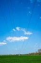 High metal electricity pylons with power lines that pass over an agricultural field, against the backdrop of a blue sky Royalty Free Stock Photo