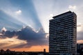 High modern building with sun rays penetrating the dark clouds