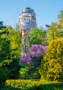 High modern high-rise building on the background of blossoming trees and green bushes