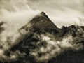 High mountain peak covered by fog and mist