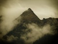 High mountain peak covered by fog and mist