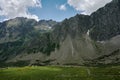 High mountain range landscape with rocky hills, river, green valley and white clouds Royalty Free Stock Photo