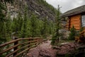 High mountain village - a stone path, a wooden fence in the middle of a coniferous forest and the slopes of the Rocky Mountains.