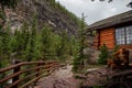 High mountain village - a stone path, a wooden fence in the middle of a coniferous forest and the slopes of the Rocky Mountains.