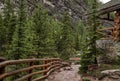 High mountain village - a stone path, a wooden fence in the middle of a coniferous forest and the slopes of the Rocky Mountains. Royalty Free Stock Photo