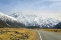 High mountains with snow at the top and highways in winter. The grass on the roadside is yellow in the National Park area