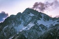 High mountains with snowy peaks at sunset in clouds and fog