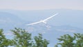 High performance turning glider at very low altitude just above the treetops