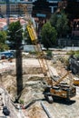 High perspective view of a busy construction area, including laying foundations, manual workers, machinery, cranes and pouring