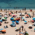 High perspective view of many people at Pescadores Beach in Ericeira sunbathing during the