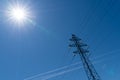 High power electrical lines electricity pylon in blue sky with sun Royalty Free Stock Photo