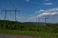 High power lines in a green area against a blue sky with white clouds. Royalty Free Stock Photo