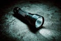High-powered flashlight resting on a concrete surface in a dimly lit environment during nighttime Royalty Free Stock Photo