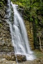 A high and powerful waterfall deep in the forest, surrounded by grass, rocks, trees Royalty Free Stock Photo