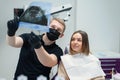 High-qualified dentist shows the young female patient an X-ray of the teeth in the dental chair at modern clinic.