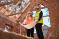 High-qualified foremen looking at blueprint, standing inside building