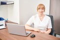 High-qualified woman doctor waiting for client sitting in workplace with laptop