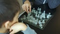 High quality close-up photo of a young man playing glass chess with his little son. Father and son time together at home. Smart Royalty Free Stock Photo