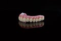 High-quality dental prosthesis made by dental technician, prosthesis with a pink gingiva to fix after implantation.