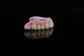 High-quality dental prosthesis made by dental technician, prosthesis with a pink gingiva to fix after implantation.