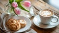 Coffee cup and pastries with tulips on wooden table