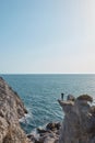 a man stands on the edge of a cliff, hands spread out in different directions, seascape and mountains