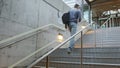 High quality picture of a young man who climbs the stairs at the station and holds a phone in his hands and a backpack on his back