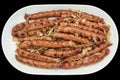 Freshly Barbecued Bratwurst Sausages Served with Minced Onion on Oblong Porcelain Tray Isolated on Black Background