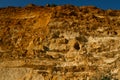 High red brown yellow sandy textured cliff of Fiolent with holes on the Black Sea coast in the light of sunset. South Crimea. Blue Royalty Free Stock Photo