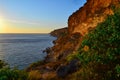 High red yellow sandy long cliffs of Fiolent with dry grass and green bushes on Black Sea coast in the light of sunset. Blue sky Royalty Free Stock Photo