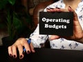 High resolution hand holding black card with written text Operating Budgets - closeup shot