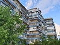 A high-rise apartment building of a slum with various old balconies against a background of blue sky and trees Royalty Free Stock Photo