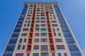 A high-rise building against a blue sky. A new high-rise residential building with a colorful facade