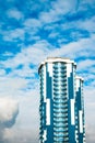 High-rise building with a glass facade against a bright blue sky with figured clouds Royalty Free Stock Photo