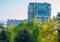 High-rise building with many windows and glass balconies on the background of the tops of trees with yellow and green Royalty Free Stock Photo