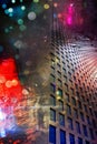 High-rise building windows. Colored lights of the night city reflect. Raindrops on a wet window glass. Abstract.