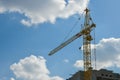 High-rise construction crane with a long arrow of yellow color against the blue sky over a new multi-storey building of concrete Royalty Free Stock Photo