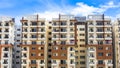 A high rise modern apartment complex in suburban Bangalore against a blue sky on a sunny day.